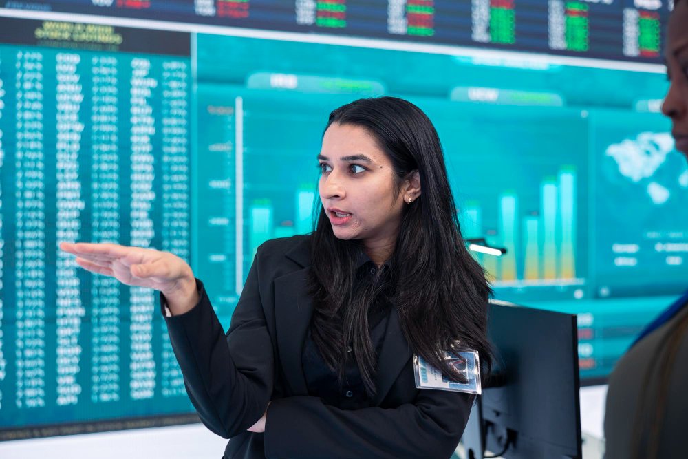 Financial analyst explaining stock market trends on digital trading screens during global market volatility