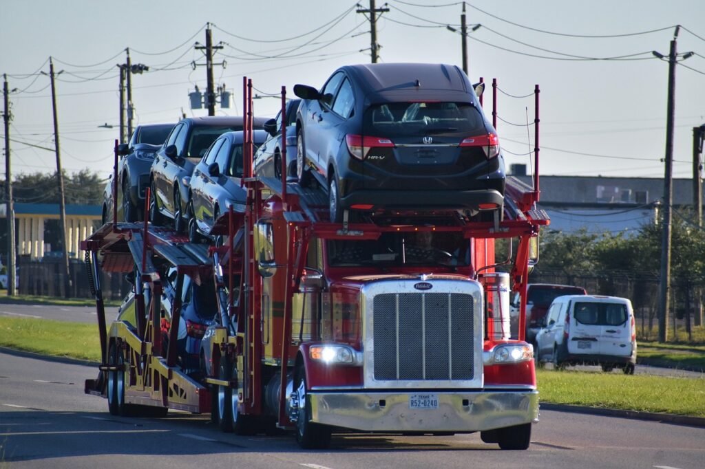 Red luxury convertible being loaded into enclosed auto transport trailer for secure car relocation.