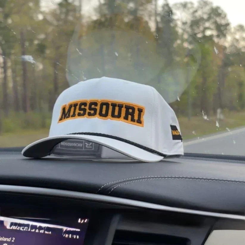 White Missouri rope hat with black-and-gold lettering and a black rope detail on a car dashboard